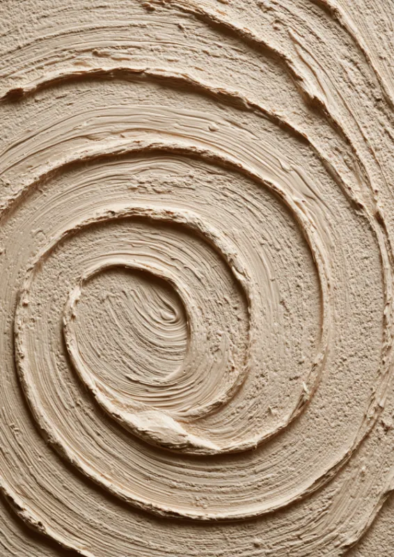 Close-up van een perfecte concentrische spiraal gebeeldhouwd in warme zandige klei die een meditatief zen patroon creëert